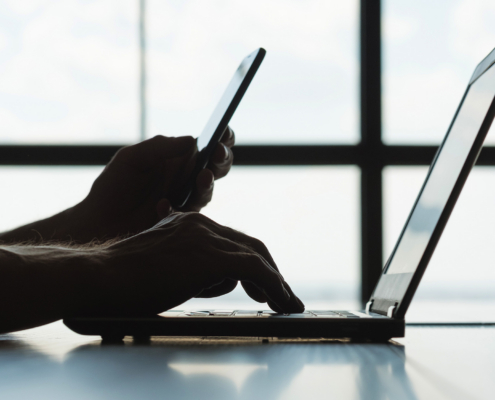 Person Looking At Phone And Laptop